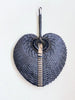 product photo of small black bohemian handwoven palm leaf fan hanging on white wall