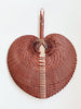 product photo of small burgundy bohemian handwoven palm leaf fan hanging on white wall