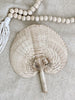 small natural handwoven palm leaf fan next to natural bohemian wooden bead tassel