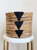 medium brown handwoven banana leaf plant basket pot with black triangle design on white stool