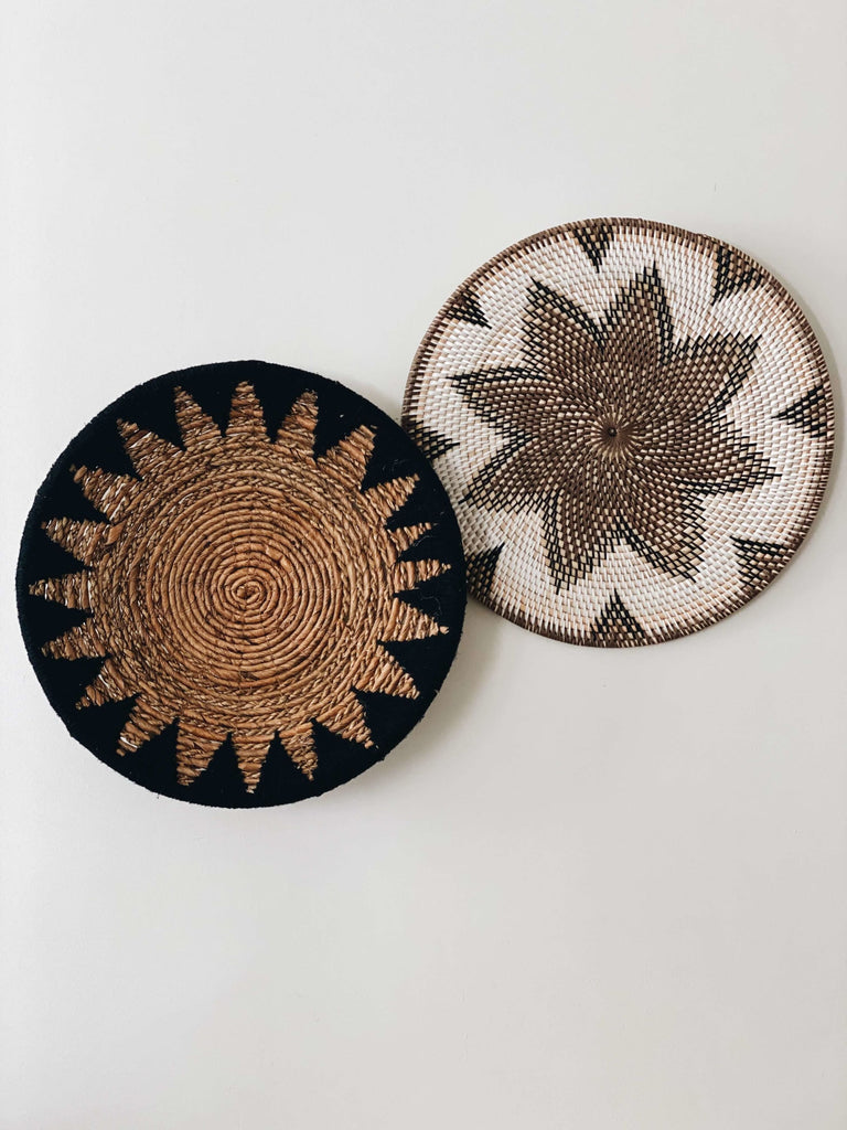 pair of handwoven rattan brown and white wall basket and banana leaf brown and black wall basket hanging on white wall