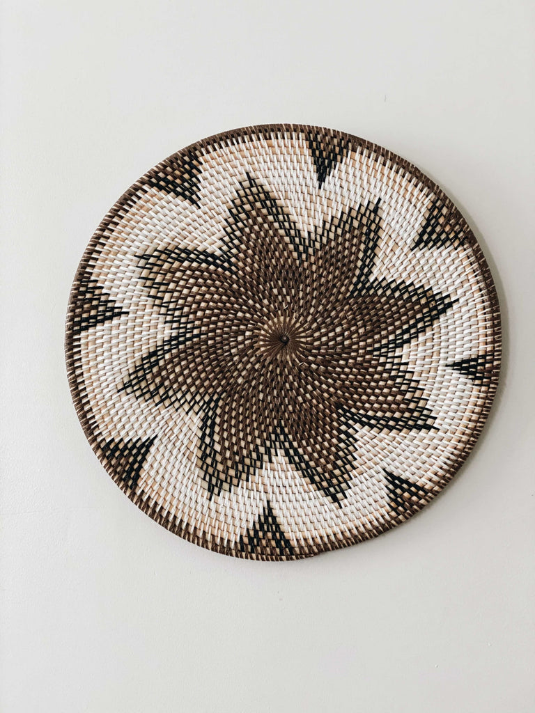 bohemian handwoven rattan brown and white wall basket hanging on white wall