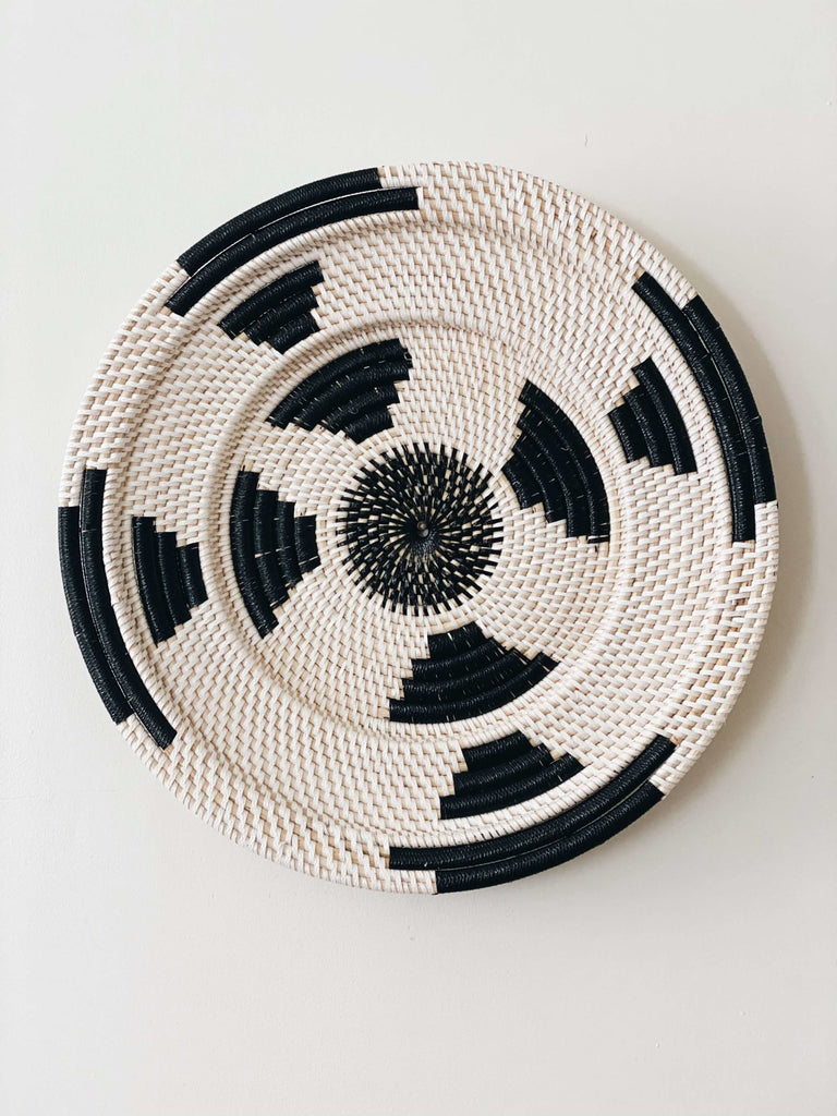 black and white handwoven rattan wall basket hanging on white wall