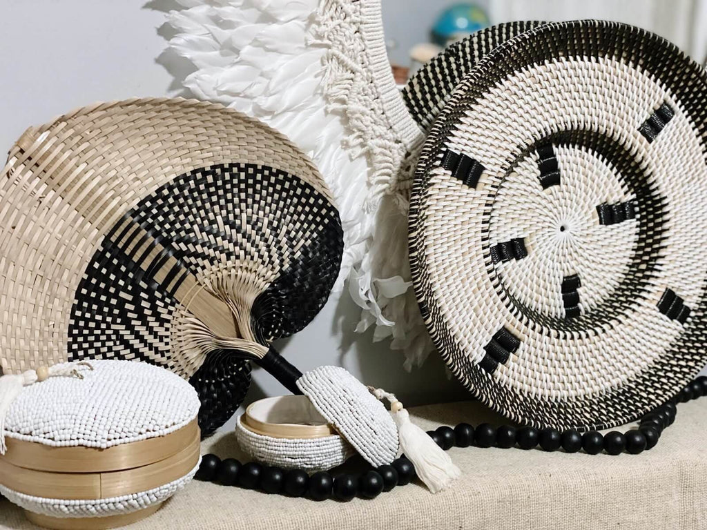beautiful arrangement of black and white bohemian home decor with handwoven rattan wall basket and palm leaf fan