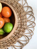wooden fruit bowl on top of boho woven straw placemat