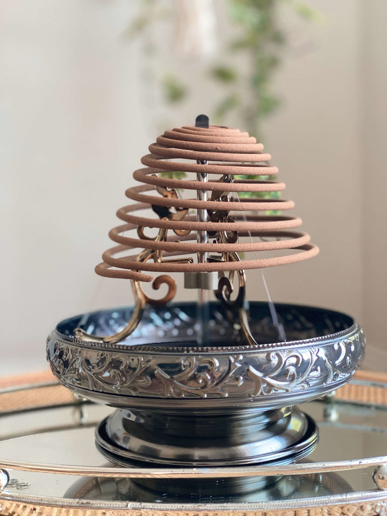 magical silver incense coil holder with a spiraling incense burning 