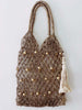 jute bag fishetnet totebag with hanging tassel charm accessory on white wall