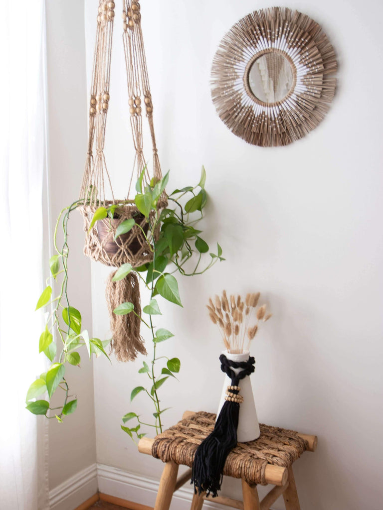 bohemian husk mirror decor next to beaded macrame plant hanger with pothos and pampas in a bohemian corner