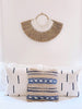 beaded grass fan wall hanging on top of bed with african mudcloth pillows in modern bohemian bedroom