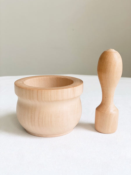 mini handcarved natural wooden mortar and pestle on white kitchen table 