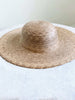 handwoven bohemian brown palm leaf sombrero on white table