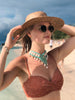 beautiful woman in bathing suit wearing brown handwoven palm leaf sun hat at the beach