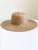handwoven bohemian brown palm leaf sombrero on white table