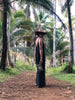 woman walking in the jungle wearing a brown bohemian woven straw hat