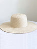 handwoven bohemian cream palm leaf sun hat on white table
