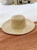 bohemian vanilla cream handwoven palm leaf sun hat on bohemian bed with macrame pillows