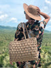 girl on vacation wearing a handwoven brown palm leaf sun hat and straw bag in the tropics