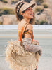 happy woman in bohemian fashion wearing brown handwoven palm leaf sun visor in malibu beach PCH