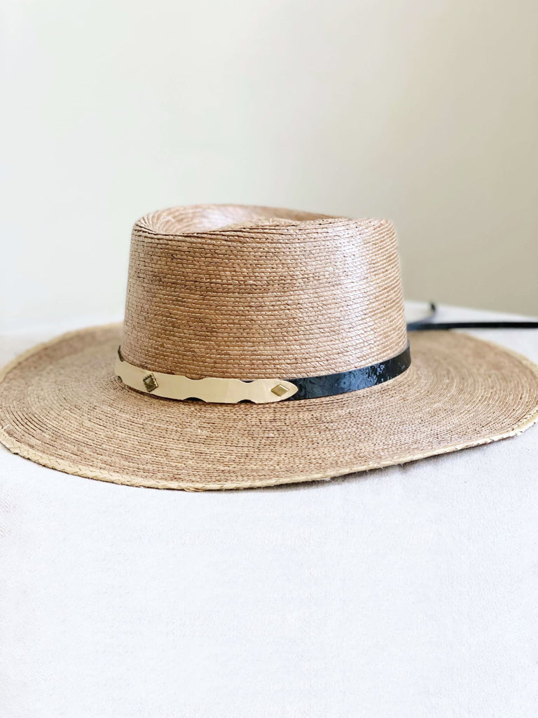 bohemian brown handmade palm leaf sun hat with black and gold accent on white table