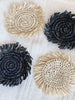 set of four natural and black handwoven raffia fringe coasters on detailed white table cloth