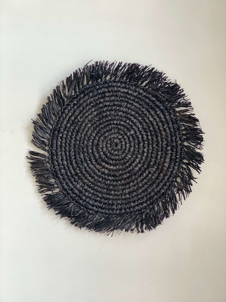 product photo of bohemian handwoven black raffia fringe placemat on white surface