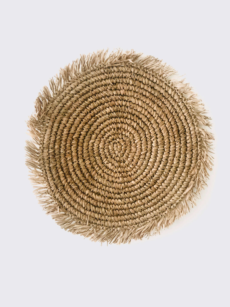 product photo of bohemian handwoven natural raffia fringe placemat on white surface