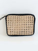 product photo of detail on bohemian rattan and black leather market fanny pack on white surface