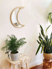 large rattan crescent moon mirror in scandi bohemian bedroom with tropical plants and boho decor