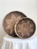 set of two brown bohemian handwoven rattan nesting trays laid upright on a white cloth table