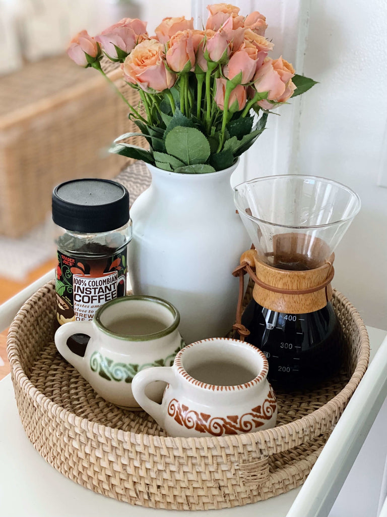 aesthetic morning coffee set up with artisanal clay mugs and pretty pink roses placed in a rattan serving tray