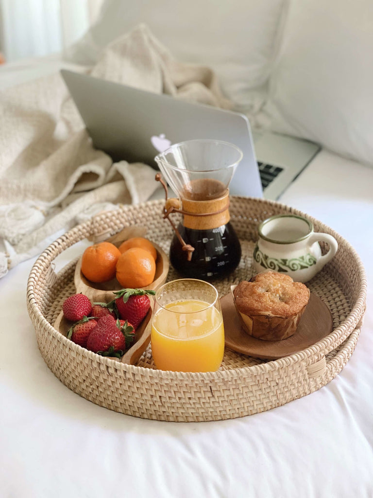 handwoven rattan nesting serving tray used for breakfast in bed on a beautiful sunny morning next to a throw blanket and macbook