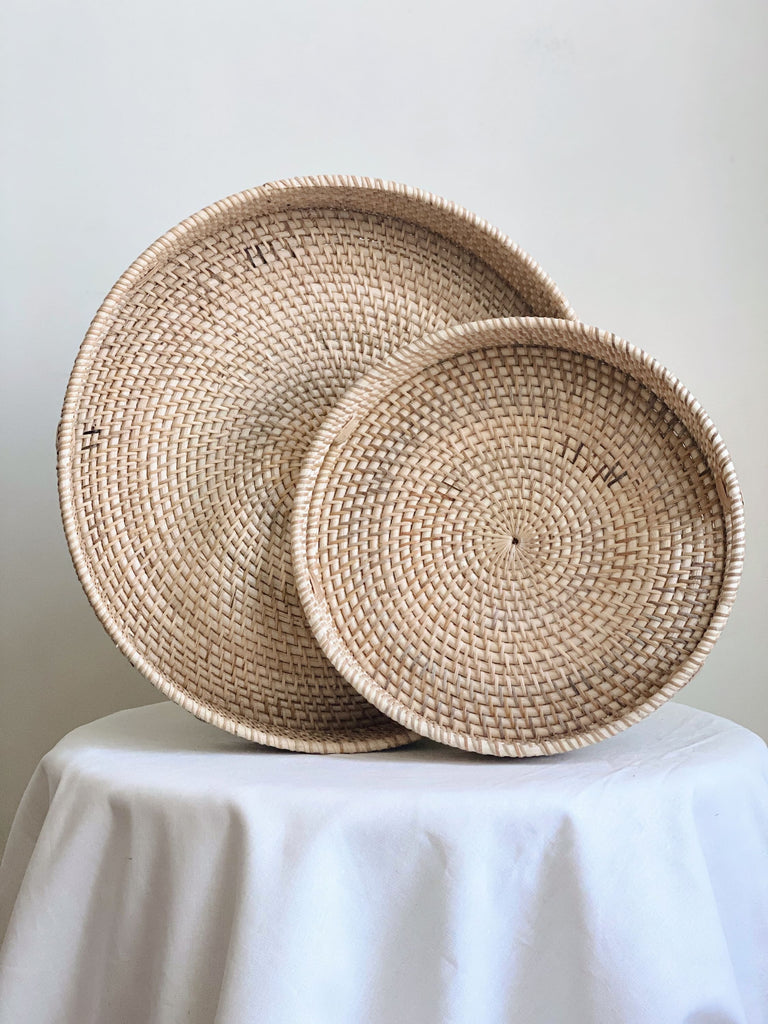 set of two natural rattan nesting trays laid upright on a white cloth table