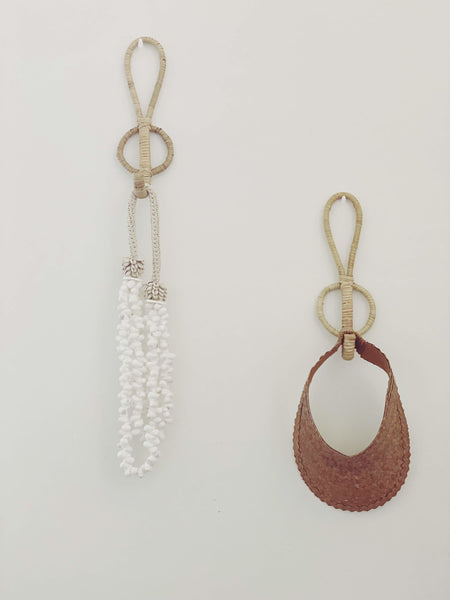 set of two rattan single hooks holding bohemian summer accessories including palm leaf visor and shell necklace