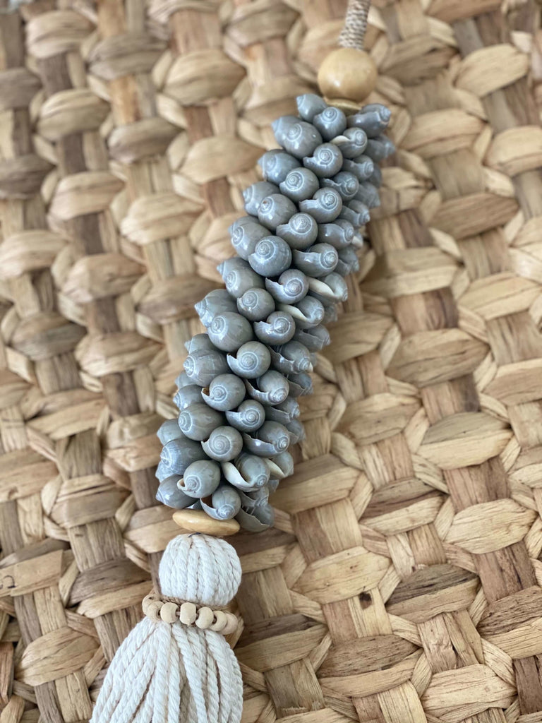 closeup of detail on handmade gray shell cluster tassel on hyacinth placemat