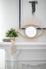 gray shell cluster tassel on mantel next to bushy home plant and open eye rattan mirror