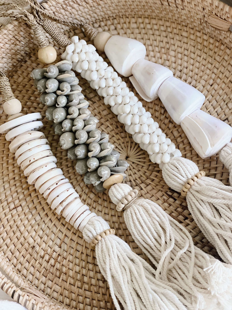 closeup of detail on set of four beautiful handmade cluster shell cotton tassels on rattan basket