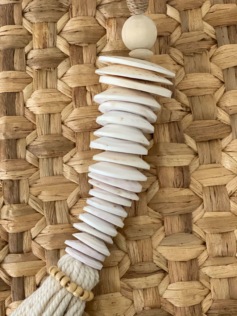 closeup of detail on stunning handmade white conus shell disc stack tassel on hyacinth placemat