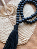 bohemian black handcarved beaded tassel laying on palm leaf fan on top of wicker furniture