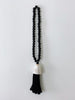 product photo of bohemian handcarved black wooden bead tassel with black conus shell hanging on white wall