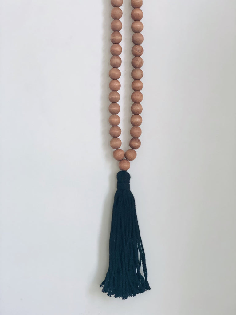 bohemian handcarved brown wooden bead tassel with black tassel hanging on white wall