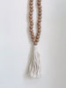 bohemian handcarved brown wooden bead tassel with cream tassel hanging on white wall
