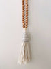 product photo of handcarved boho brown beaded conus shell tassel hanging on white wall