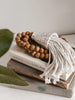 light academia vibes with boho wooden bead conus shell tassel on top of books next to plant
