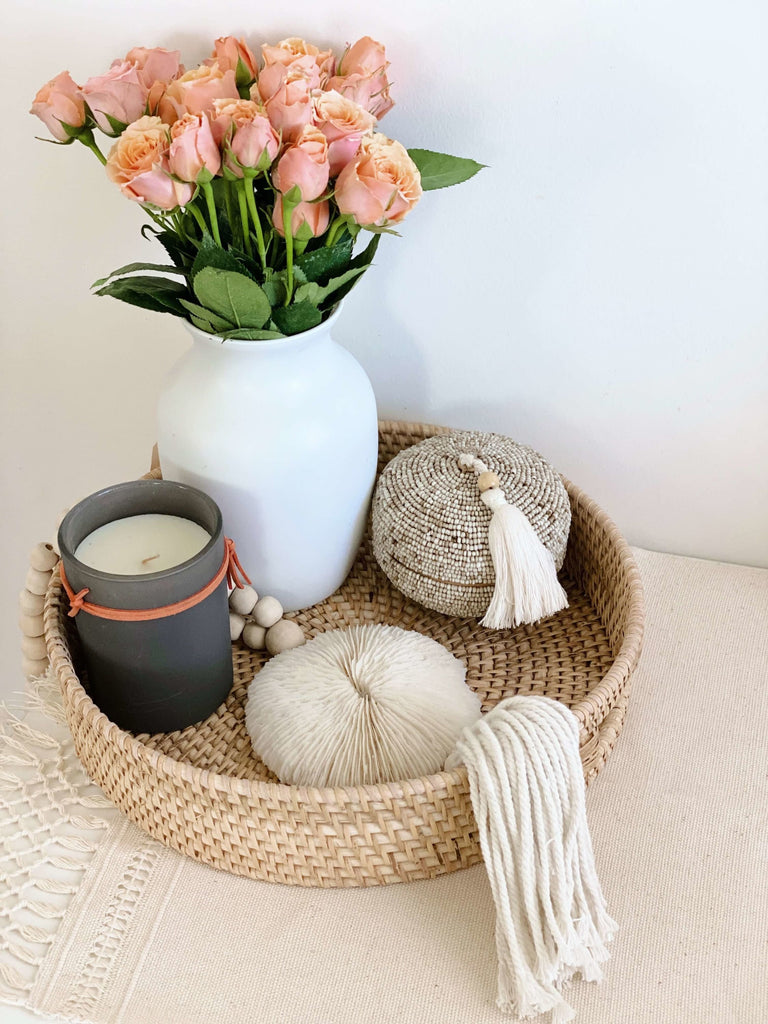 beautiful woven nesting tray decor with wooden bead shell tassel, beaded bamboo basket, vase of pink roses, and candle
