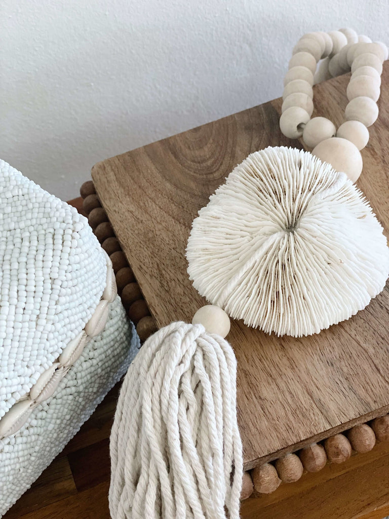 stunning natural wooden bead mushroom coral shell tassel next to beaded bamboo basket
