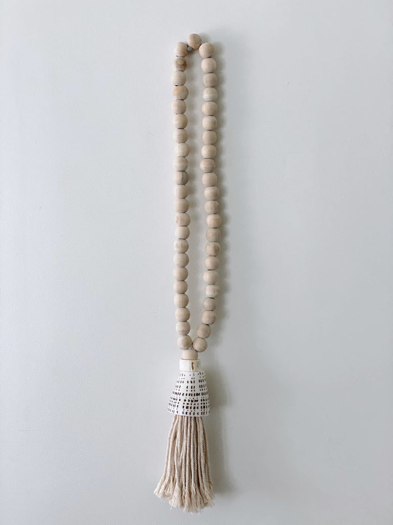 product photo of handcarved natural boho wooden bead conus shell tassel hanging on white wall