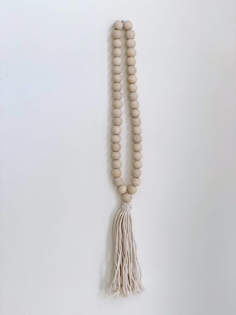 product photo of boho handcarved natural wooden bead cream tassel hanging on white wall
