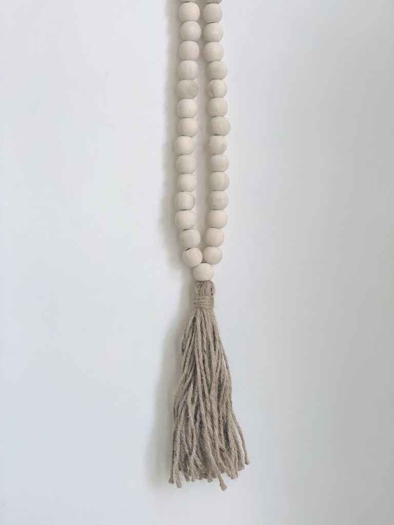 product photo of boho handcarved natural wooden bead jute tassel hanging on white wall